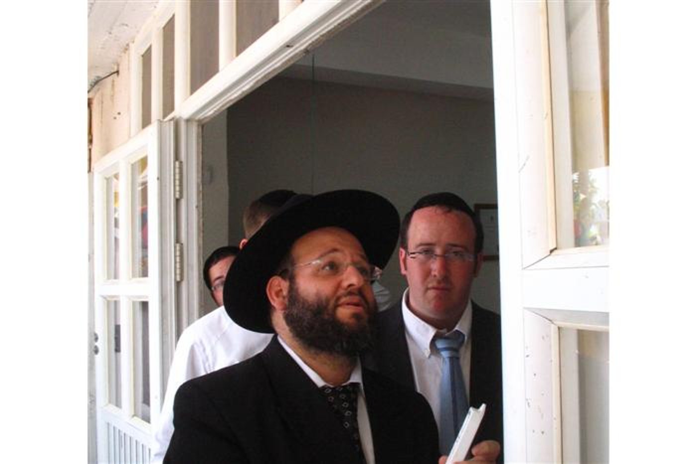 1. הרב ציון כריוסי קובע מזוזה. לצידו ר' משה גרמן, מנהל 'תיווך ירוחם'