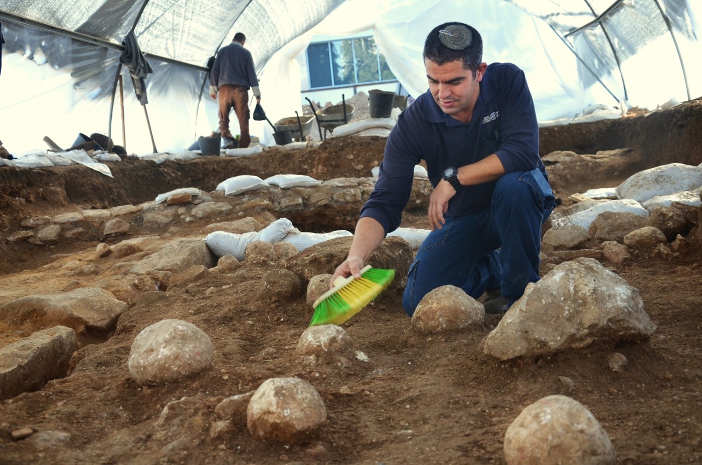 5. כפיר ארביב, מנהל החפירה מטעם רשות מהעתיקות, מנקה את אחת מאבני הקלע