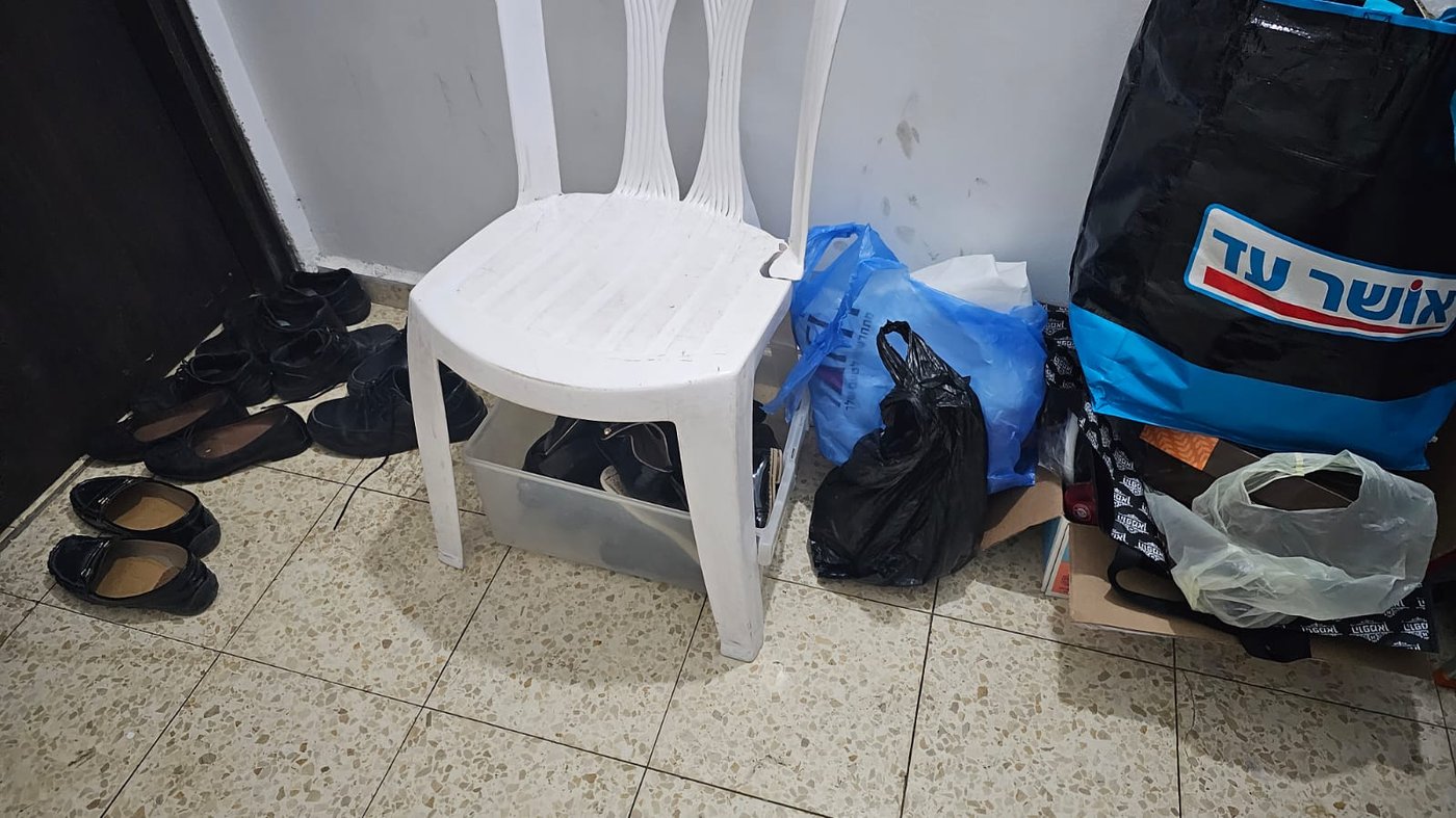 נעלי הילדים מחוץ לדלת, וכסא פלסטיק בחדר מדרגות לאכילת חמץ