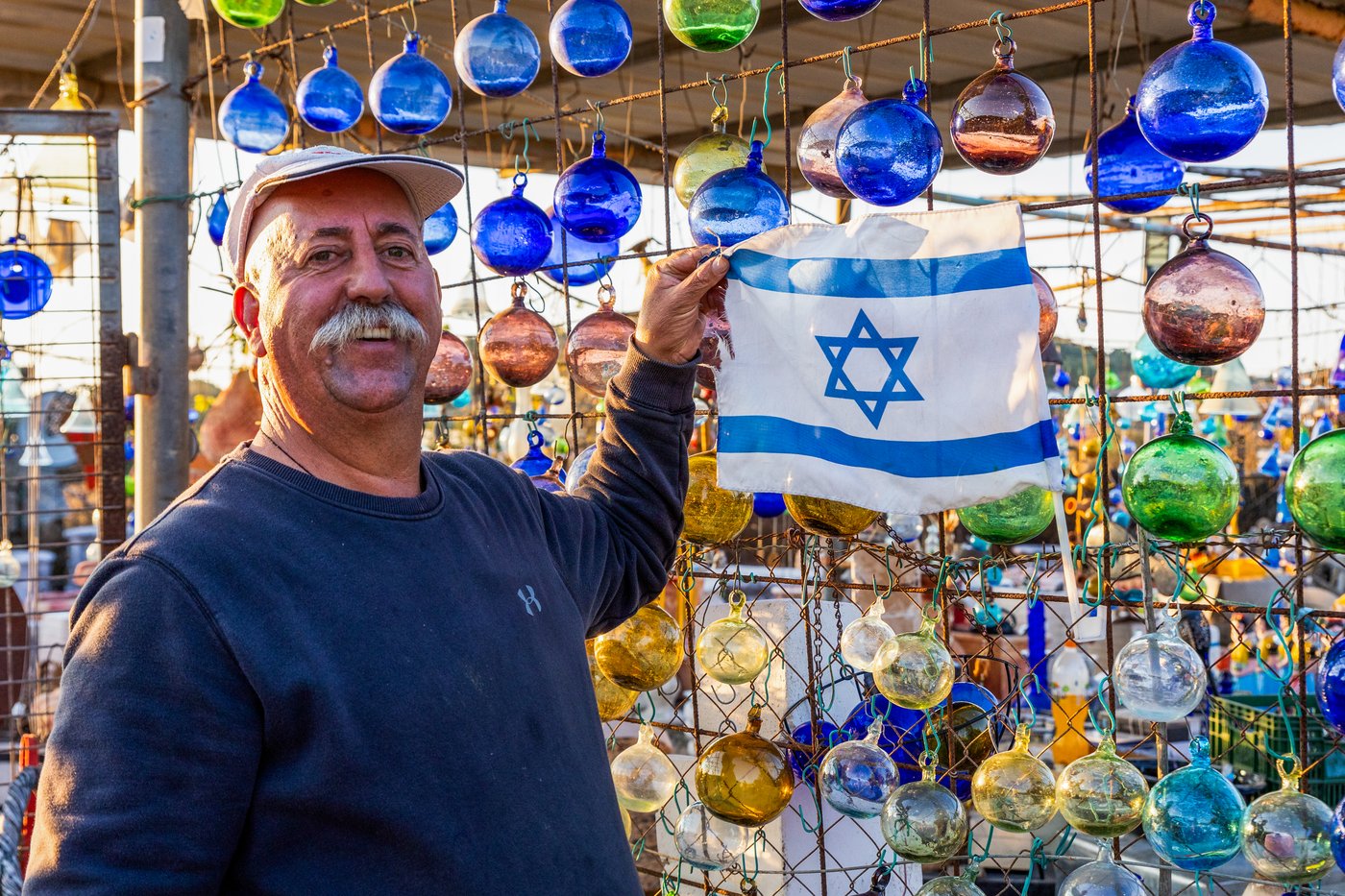 סוחר כלי זכוכית ממוצא דרוזי מניח את דגל ישראל בגוואה לצד חנותו