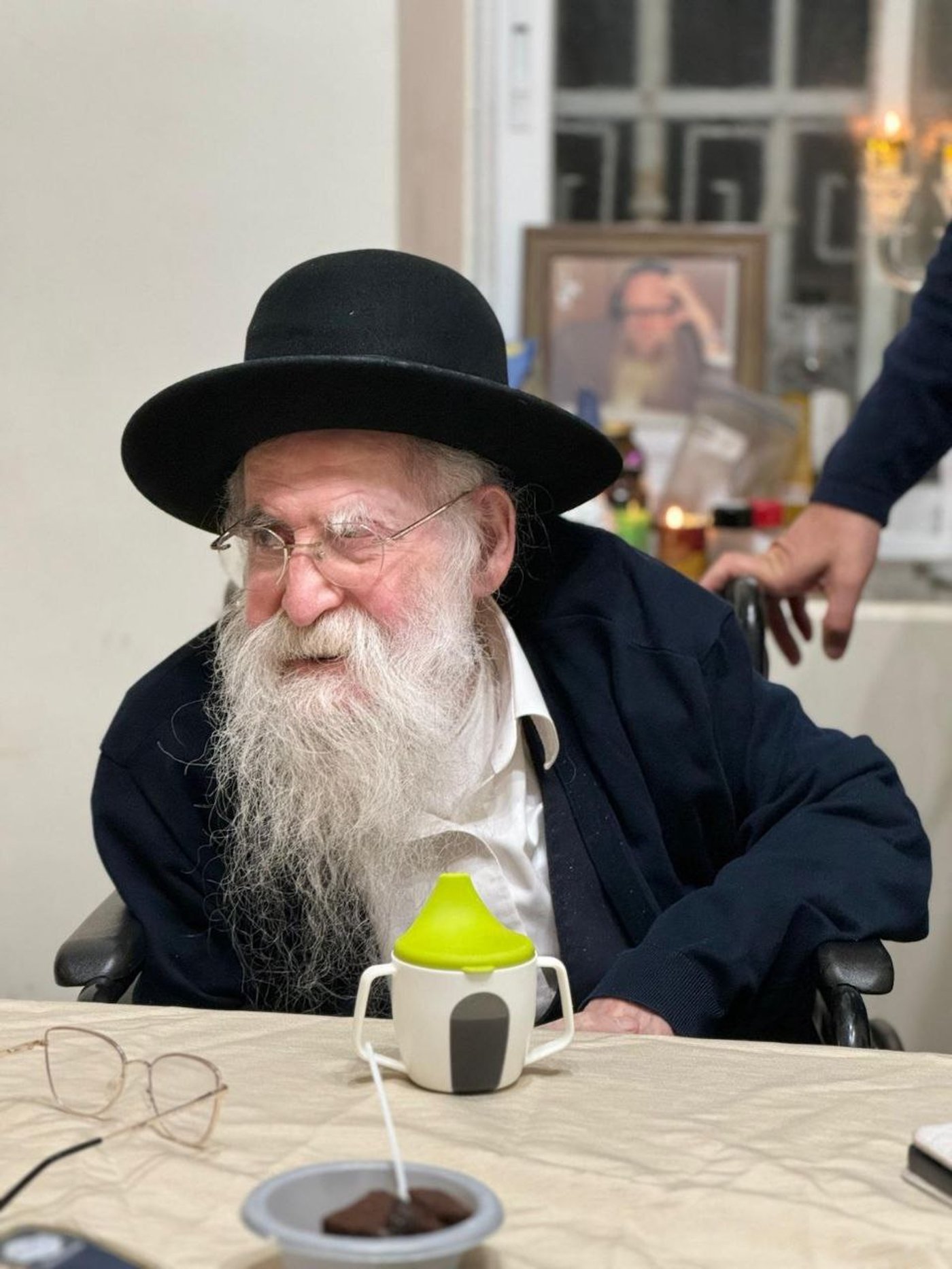 חכם משה חיים אריה זצ"ל ומאחוריו תמונתו של הצדיק רבי ששון מזרחי זצ"ל