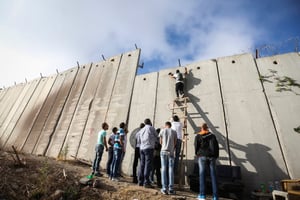 פלסטינים מטפסים על חומת ההפרדה במחסום קלנדיה