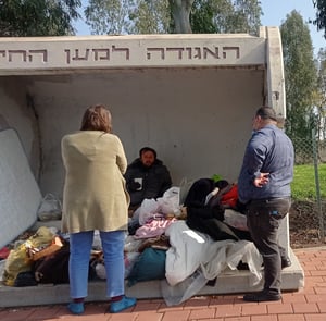 אנשים עוזרים לחסר בית שמתגורר בתחנת אוטובוס 