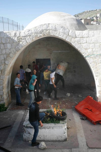 מול השוטרים הפלסטינים: פורעים הציתו את קבר יוסף