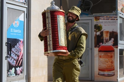 חייל מחזיק בספר תורה סמוך לגבול הצפוני