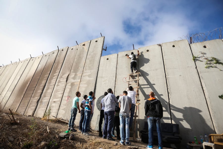 פלסטינים מטפסים על חומת ההפרדה במחסום קלנדיה