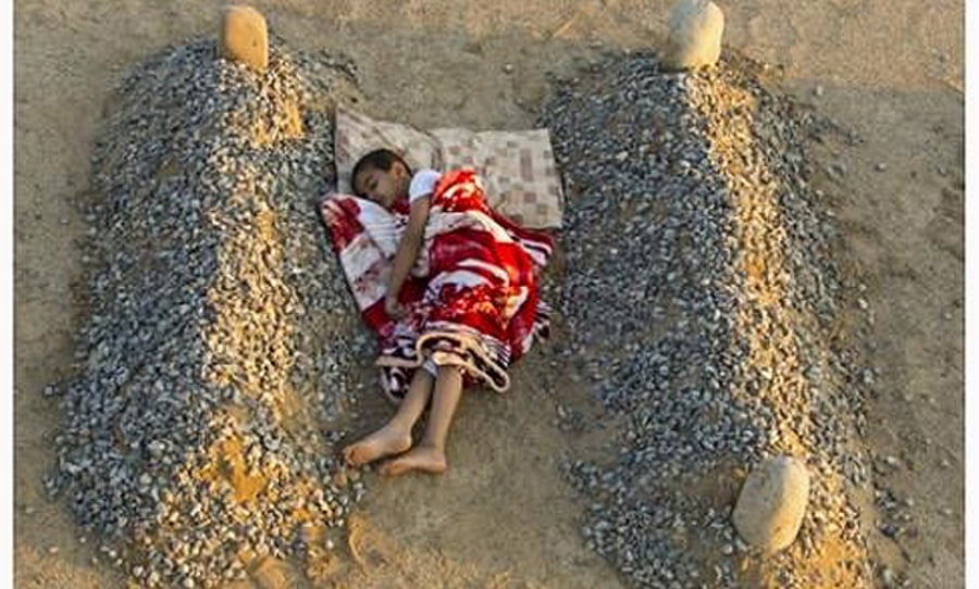 ילד סורי ישן ליד קברי הוריו