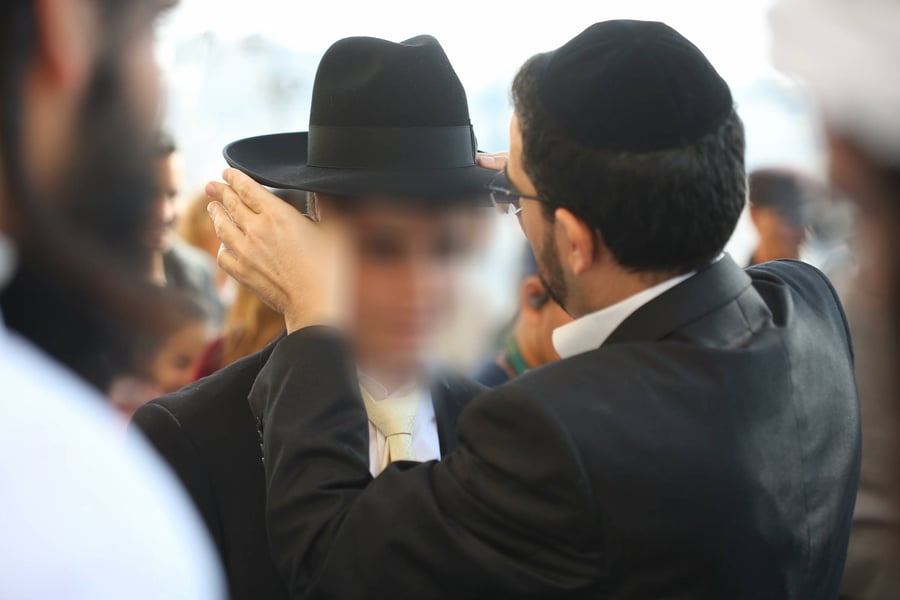 הרב משה כהן מיד לאחים חובש את המגבעת לראשו של חתן הבר מצווה.
