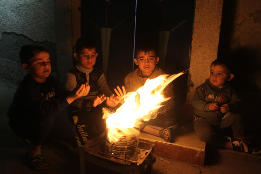 ילדים עזתיים מתחממים ליד מדורה ממחסור בחשמל