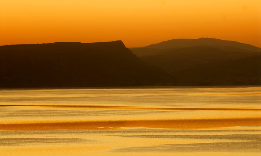 השתקפות שקיעת השמש על אגם הכנרת. ברקע, הר הארבל