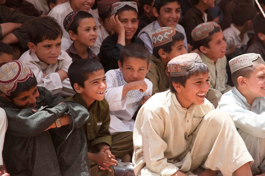נערים אפגנים מחייכים במהלך טקס וסיום הלימודים בבית הספר במחוז ספין בולדק, מחוז קנדהאר, אפגניסטן