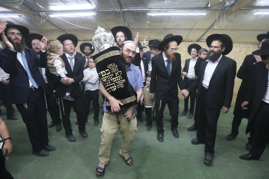 ותומכיה מאושר. הזוכה ר' אסף ארצי רוקד עם ספר התורה בבית הכנסת
