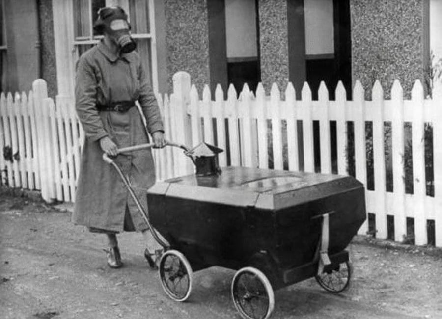 אם עטויית מסכת גז, המובילה תינוק בעגלה חסינת גז