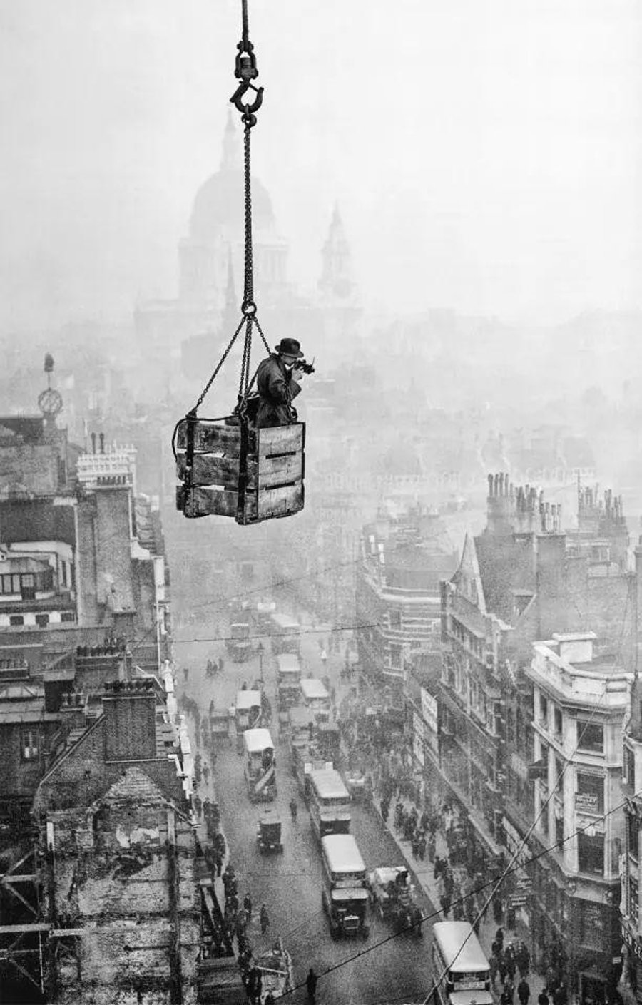 1929, בריטניה: הצלם ר.ג. סלומון מצלם את העיר לונדון, מתוך ארגז המתנדנד בשמי העיר ותלוי על מנוף