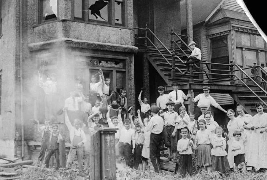 ילדים לבנים מחוץ לבית משפחה שחורה שהעלו באש במהלך 'הפגנות הגזע'. שיקגו, 1919
