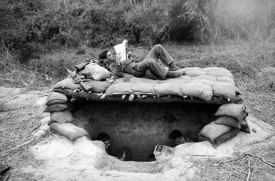 מנוחת צהריים: חיילים אמריקנים קוראים עיתונים בשוחה בג'ונגל. גבול קמבודיה-ווייטנאם 1966