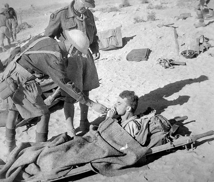 חיילים בריטיים מציתים סיגריה של חייל איטלקי פצוע באל-עלמיין. מצרים 1942