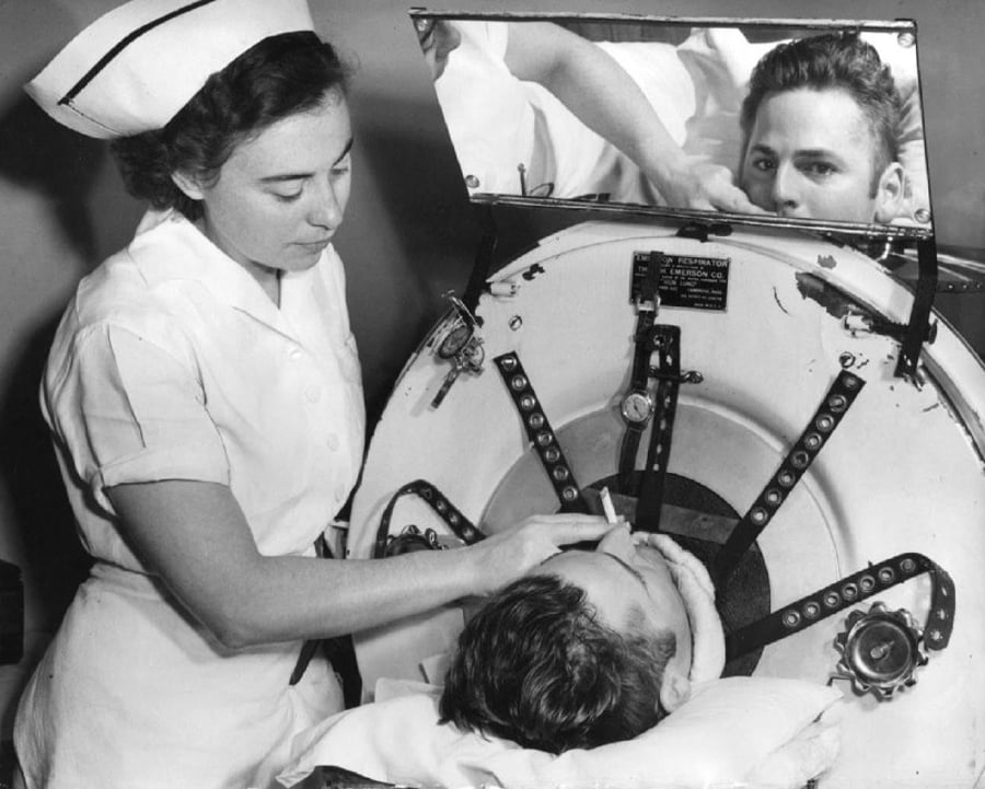 אחות בבית החולים מסייעת לצעיר המטופל בריאת ברזל ב... עישון סיגריה. ארה"ב 1949