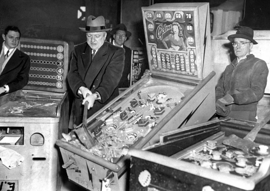שוטר מנפץ מכשיר לא חוקי למשחקי פינבול בביקורת במפעל הייצור. ברוקלין ניו יורק ארה"ב 1945