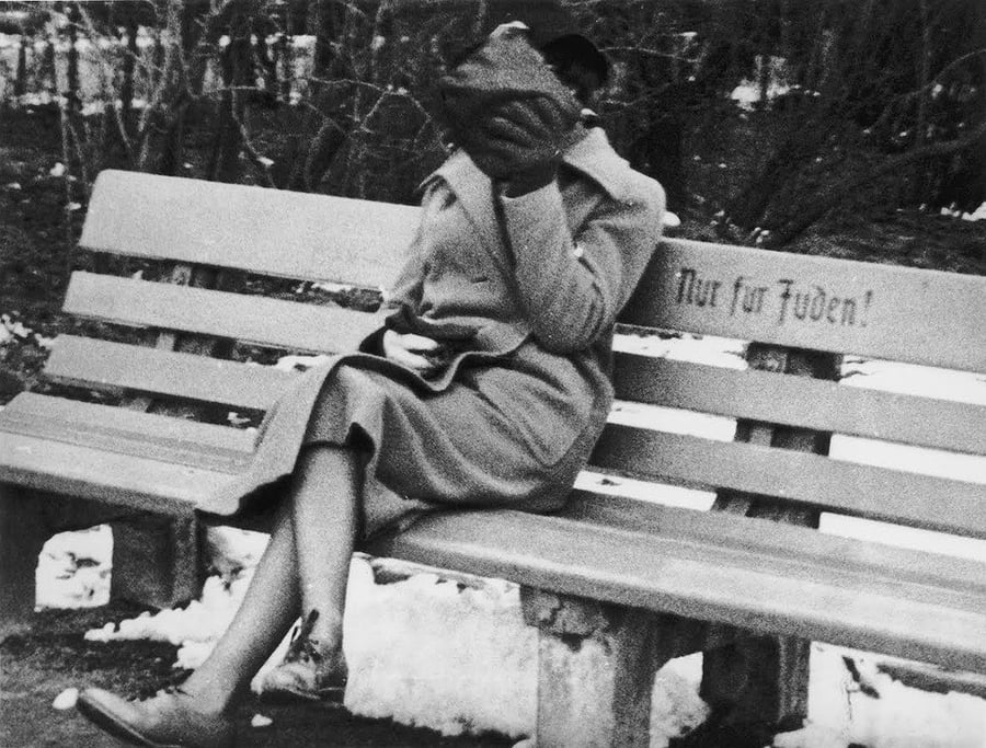 יהודיה יושבת על ספסל המסומן 'ליהודים בלבד', ומכסה את פניה בבושה. אוסטריה, 1938