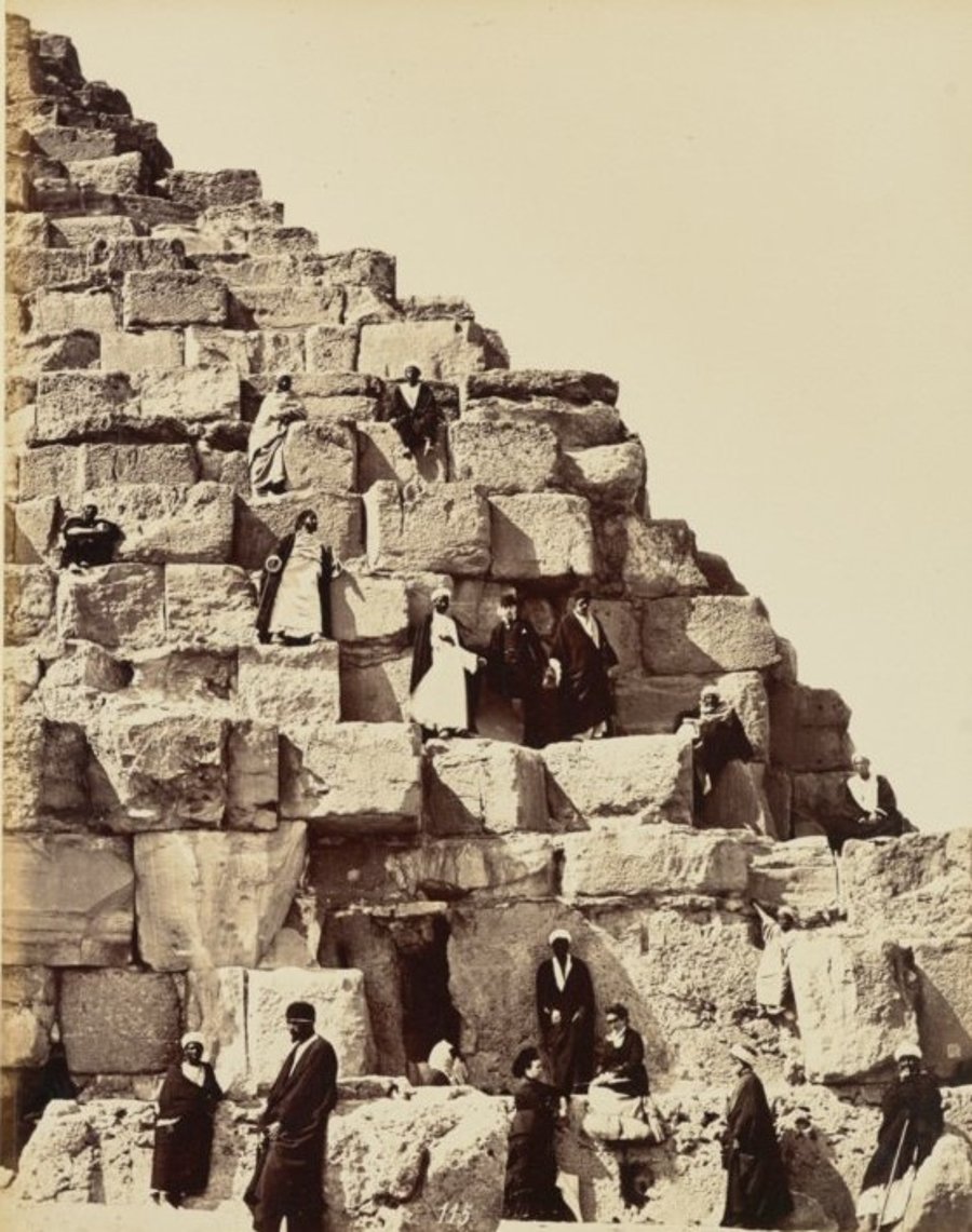 תמונה קבוצתית בפירמידות. נראים מצרים בלבוש מסורתי ושתי נשים אירופאיות. גיזה מצרים בשנות ה-1870