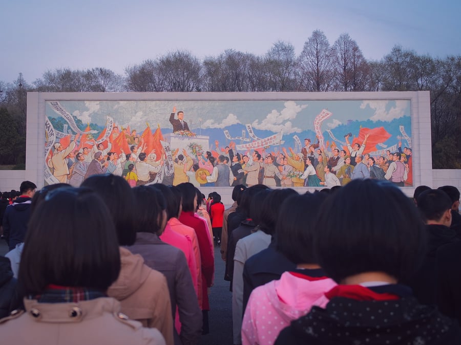 ילדים עומדים בתור מול ציור קיר בפיונגיאנג, צפון קוריאה