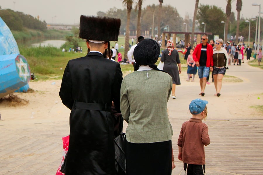 משפחה חרדית מטיילת ליד חוף הים באשדוד, בחג הפסח