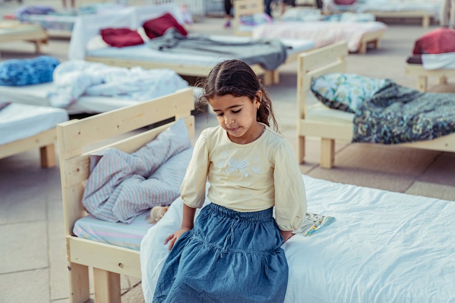 ילדה יושבת על מיטה במיצג מיטות החטופים ברחבת עיריית ירושלים