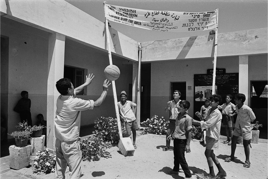 מדריך משחק בכדור עם ילדים ערבים, במחנה קיץ לילדים ב "דיר אל-בלח" ברצועת עזה, בשנת 1971
